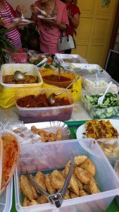 Food! Background-  various curries and sambals for nasi lemak with eggs and cucumber.  Foreground- chicken nuggset on the left and yam cake in the right. Curry puffs right in the front.