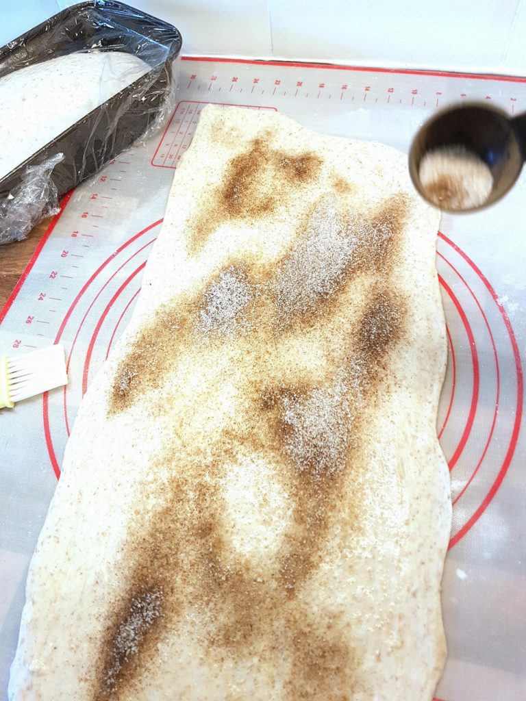 Sprinkling cinnamon sugar on to the dough.